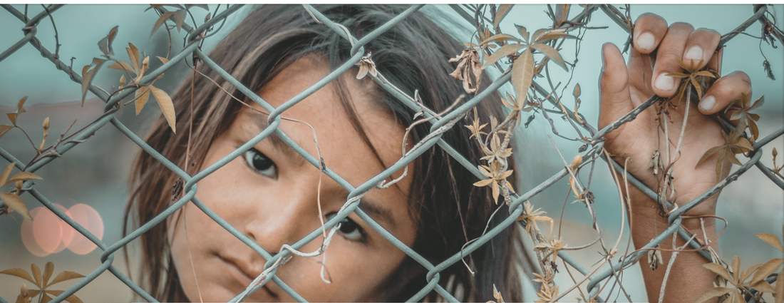 Child looking through a chain-link fence